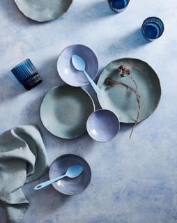 Top view of a stylish ceramic tableware set, featuring pastel-colored plates, bowls, and cups on a
