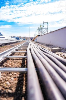 Several pipes run across a roof covered with pebbles under a blue sky, PV assembly. OBI Baumarkt,