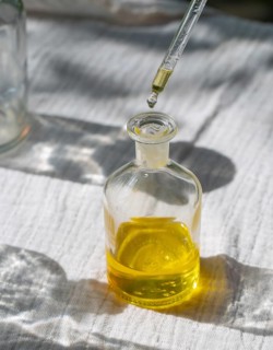 A pipette dispensing oil into a small glass bottle. Perfect for illustrating topics related to