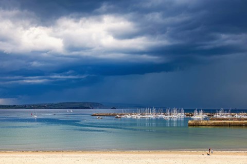 Boats in the harbor with dark thunderclouds in the sky over the sea, Crozon peninsula, Morgat,