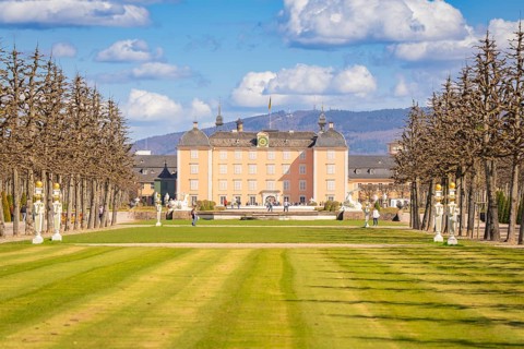 Palace with extensive garden and sculptures under a blue sky, Schwetzingen Palace Gardens, Germany