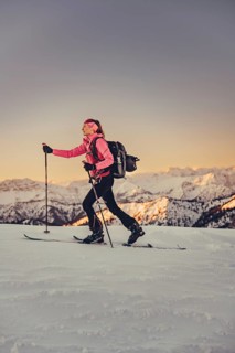 A woman's ski tour at sunrise on the Tegelberg in the Allgäu in the Ammergebirge, Bavaria, Germany