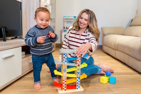 Happy mother and her baby boy enjoying playtime together with a car ramp toy in their modern living