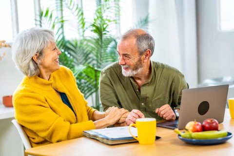 Senior woman celebrating good news while doing the household accounting with her husband sitting on