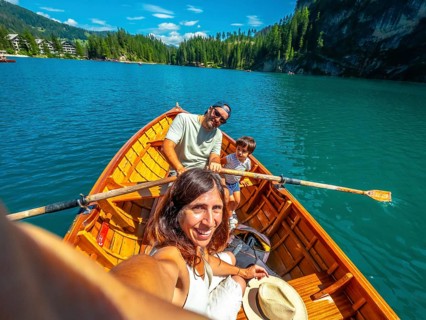 Family taking a selfie while rowing a wooden boat on the beautiful lake braies, surrounded by