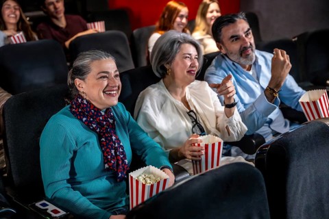 Laughter fills the air as friends and family enjoy popcorn while watching an exciting movie in a
