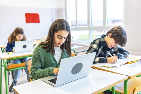 Elementary school students engaging in classroom activities, using laptops for research and
