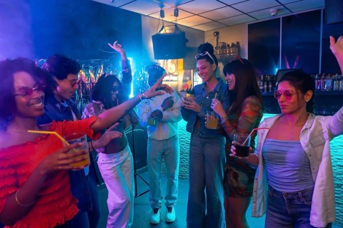 Young diverse friends enjoying music, drinks, and lively conversation in a vibrant nightclub,