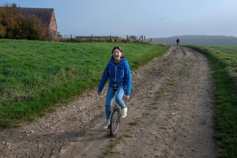 Laughing young girl, 10 years old, riding a unicycle on a dirt track, Mecklenburg-Vorpommern,