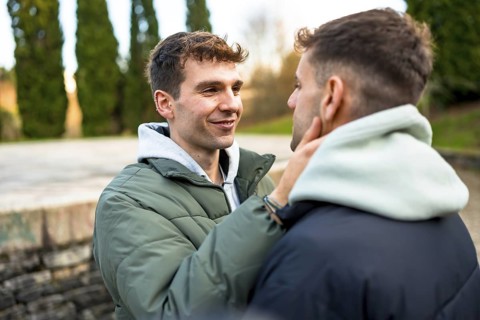 Two men embracing and smiling at each other, sharing a tender moment filled with love and intimacy