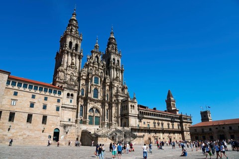 Majestic cathedral under a bright blue sky, many people in the foreground, cathedral, Santiago de