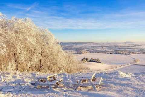 Rest area with benches and tables at a beautiful view on a hill in a frosty and snowy winter in the