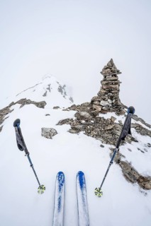 Skis and ski poles on the cloudy summit Kesch Pitschen, First Person View, Ski tour Bündner Haute