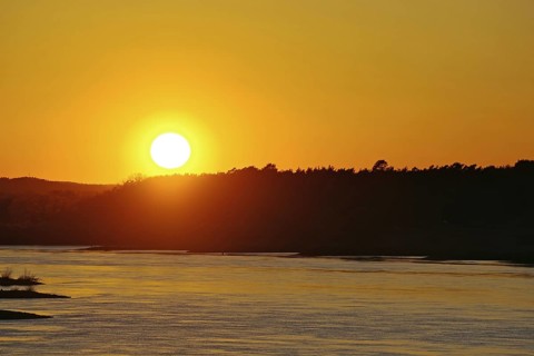 Sunset over a river with orange sky and forest silhouette, Elbe, Dömitz, Wendland, Lower Saxony,