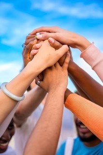 Vertical photo of hands of multi-ethnic people joining in the air
