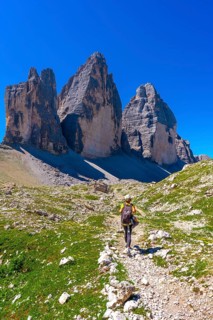 Hiker walking on a mountain path near tre cime di lavaredo in the dolomites on a sunny summer day