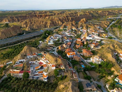Aerial view of a village in a hilly landscape with traditional houses and rugged rocks, aerial