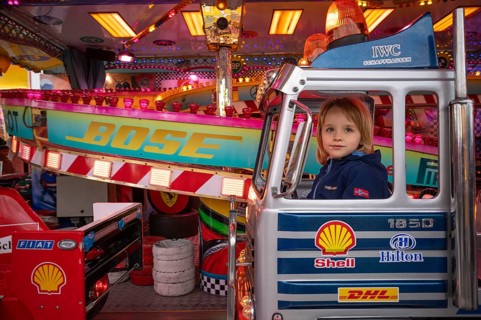 Boy, 5 years, blonde, in children's carousel, carousel, logo, Bose, Shell, Hilton, DHL, IWC