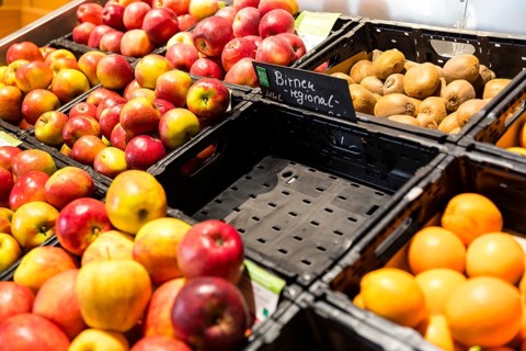 Fruit counter in a supermarket or organic food shop, here with different types of apples, kiwis,