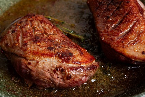 Cooking duck breast, in a frying pan, fried, with spices and herbs, close-up, no people