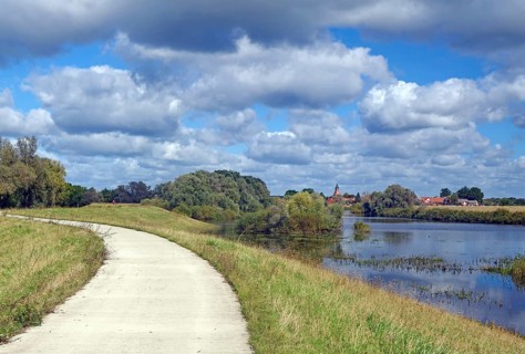 A narrow path along a river with a view of several houses and trees, Schnackenburg the smallest