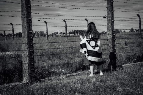 Jewish girl with Israeli flag by the fence of the concentration camp