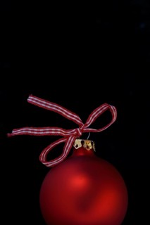 Red Christmas tree bauble with bow on a black background