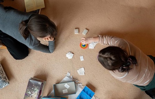Two young woman playing a parlour game on the carpet in the living room, Bavaria, Germany