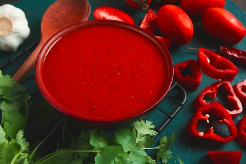 Tomato sauce, tomatoes and sweet pepper, Georgian Satsebeli sauce, with ingredients on a dark