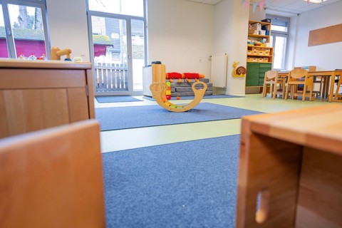 An inviting kindergarten room with a wooden rocking animal in the middle, infant and toddler