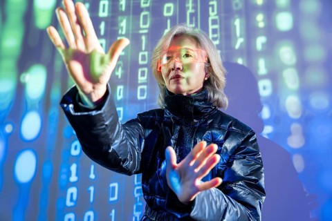An elderly Asian woman interacts with virtual elements in the metaverse, wearing futuristic glasses