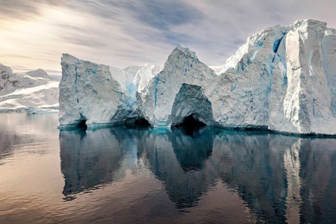 Iceberg formations are reflected in the calm water and create a mystical atmosphere, icebergs in
