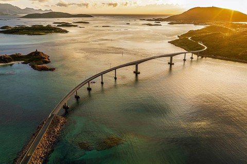 Sommaroy Bridge connecting Kvaloya Island to Sommaroy Island, warm light at sunset, aerial view,