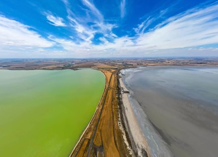 Aerial photo contrasting vibrant green and gray lakes divided by road in Victoria, Australia.