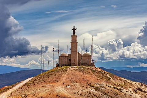 Church with statue on a mountain with antennas surrounded by dramatic clouds and a wide view, The