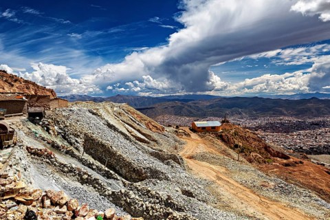 Barren mountainside landscape with buildings and dramatic sky in the background, The silver mines