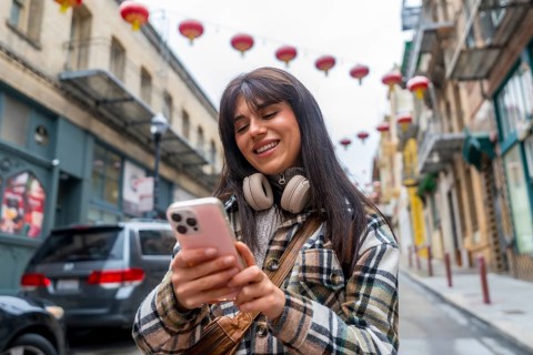 Young smiling woman exploring san francisco chinatown, browsing smartphone content and enjoying