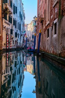 View from a gondola on a waterway in Venice going through the houses on a quiet and sunny morning