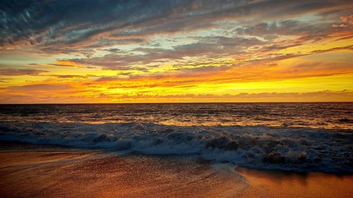 Colourful sunset over the sea with beautiful bright skies and gentle waves, hiking, Tarrafal de