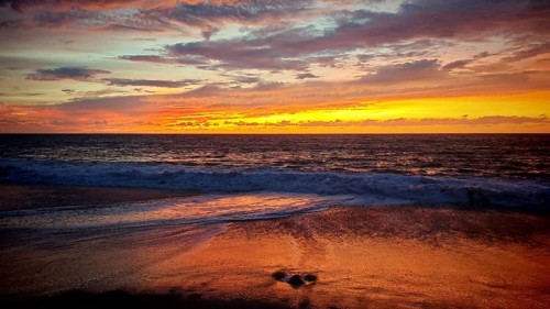 Romantic, mystical sunset with intense shades of red over the sandy beach and light swell, Tarrafal
