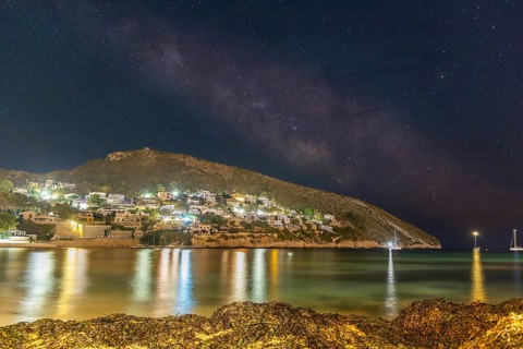 Tranquil night view of the Costa Blanca coastline under a starry sky. The lights of the houses