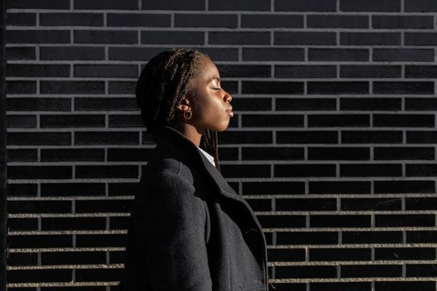 Side view of an African American businesswoman with braids, dressed in a professional coat, takes a