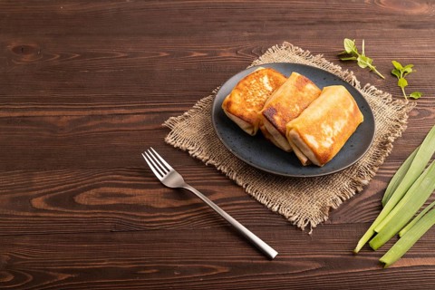 Fried crispy pancakes with meat and cheese on brown wooden background and linen textile. side view,