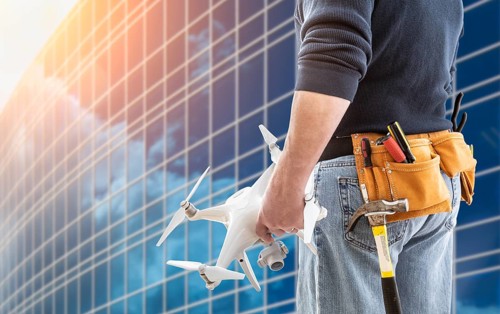 Construction Worker and Drone Pilot With Toolbelt Holding Drone At City High-Rise Building