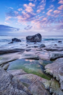 Rocks on beach of fjord of Norwegian sea in winteron sunset. Utakliev beach, Lofoten islands,