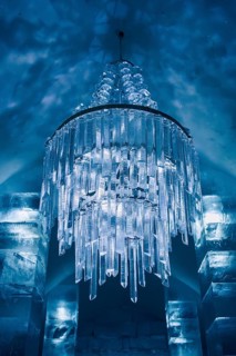 A mesmerizing ice chandelier with crystal-like shapes illuminates the temporary ice hotel in