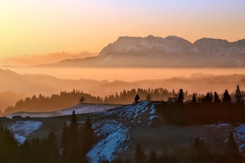 Misty morning atmosphere over hilly landscape with views of Mount Pilatus and Prealps, Entlebuch,