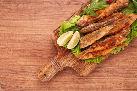 Fried crispy red mullet fish, on a wooden chopping board, with lime, no people