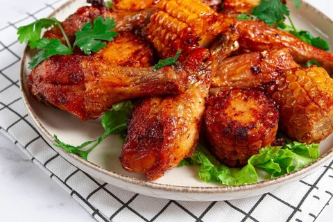 Fried chicken drumsticks, Mexican style, with corn, on a plate, close-up