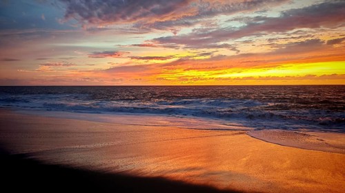 Sunset with dramatic sky and shimmering sand on the tranquil seashore, Tarrafal de Monte Trigo,